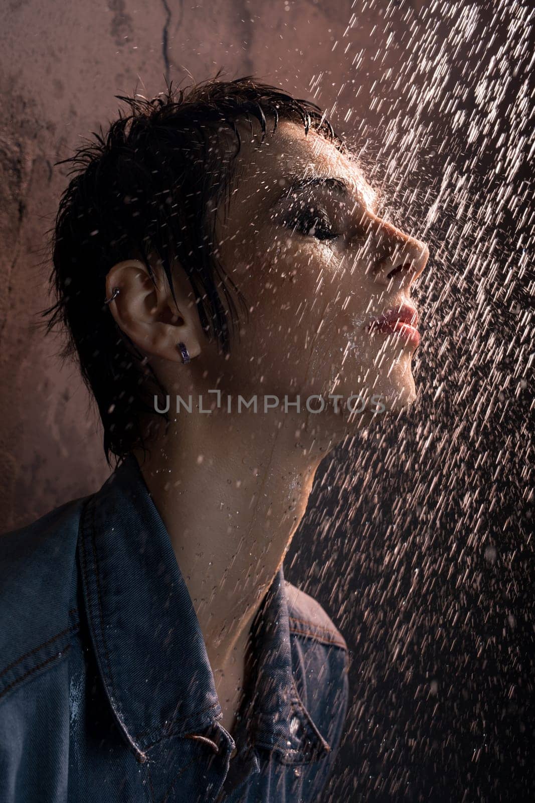 Beautiful brunette in jeans t-shirt having shower in dark room portrait