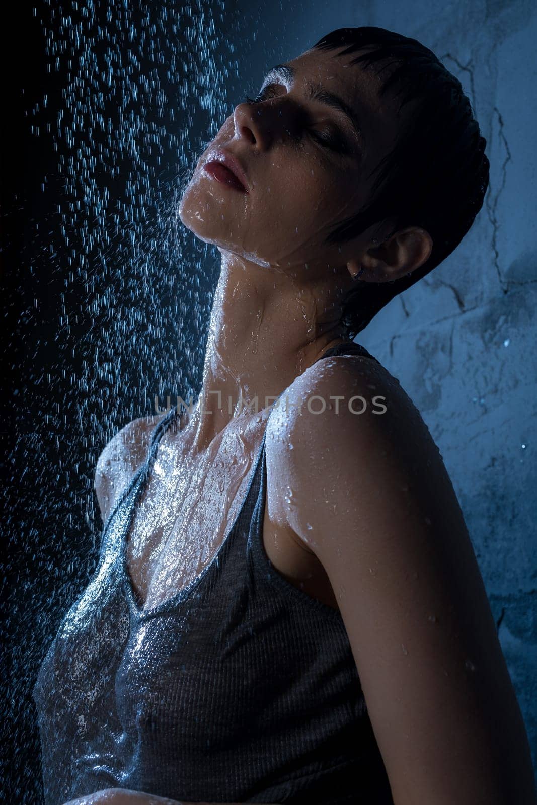 Beautiful brunette in gray t-shirt having shower in dark room portrait