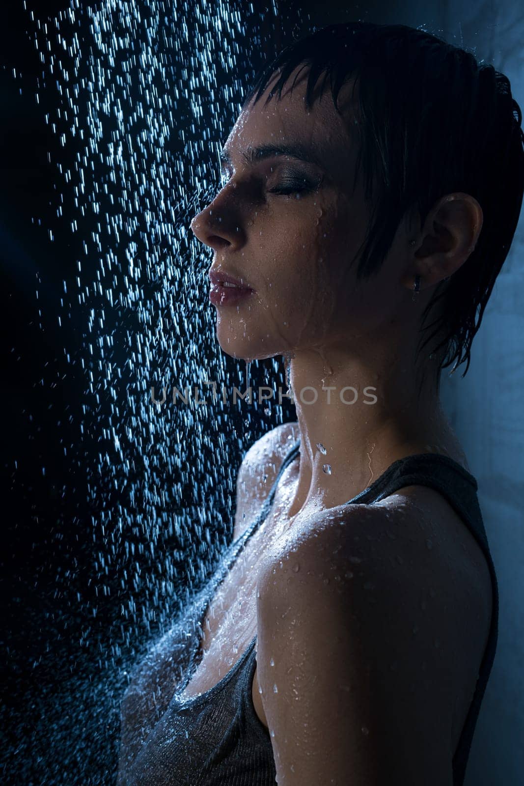 Brunette in wet t-shirt having shower in dark room profile portrait