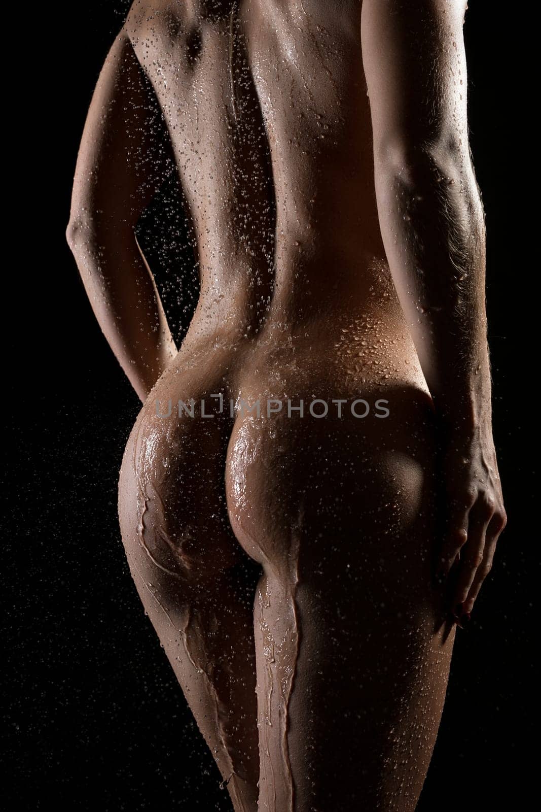 Nude slim woman body cropped rearview on black backgound