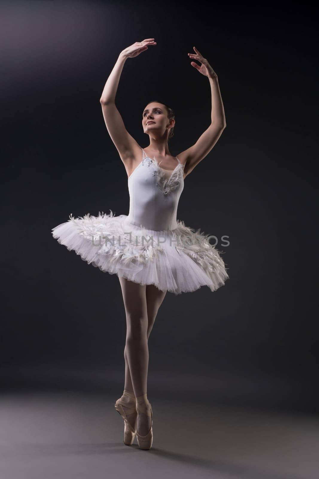 Ballerina in tutu and pointe dancing gracefully in dark room