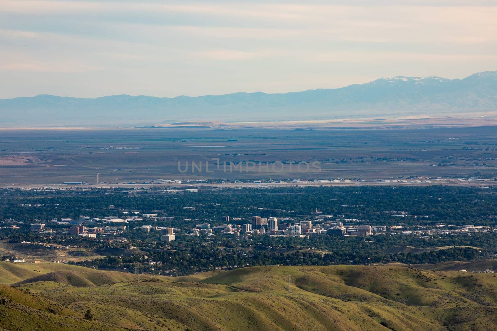 A breathtaking aerial view of Boise, showcasing the cityscape surrounded by lush greenery and distant mountains under a vast sky.