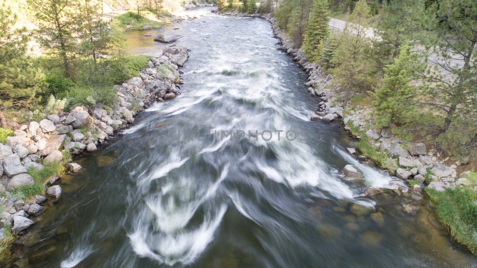 A picturesque view of a rushing river flowing through a tranquil forest. Surrounded by lush trees and rocky banks, the scene evokes peace and natural beauty.
