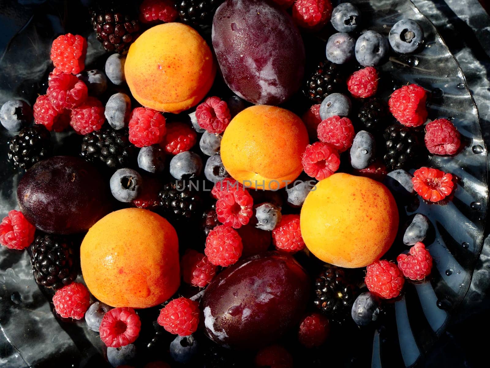 Colored background of seasonal summer fruits apricot, plum, raspberry, blueberry, blackberry in garden, close up