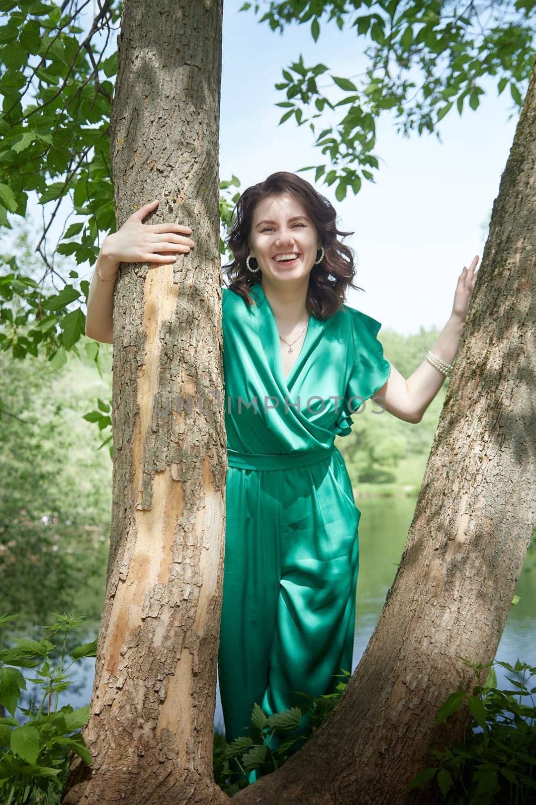 Portrait of a happy girl in the park in summer. Holidays, rest, youth. A young girl with curly hair in a green park on a summer day