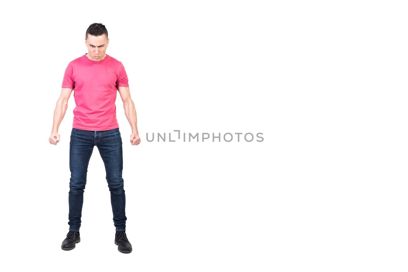 Full length angry male in jeans and pink t shirt clenching fists and looking at camera with frown while starting fight against white background