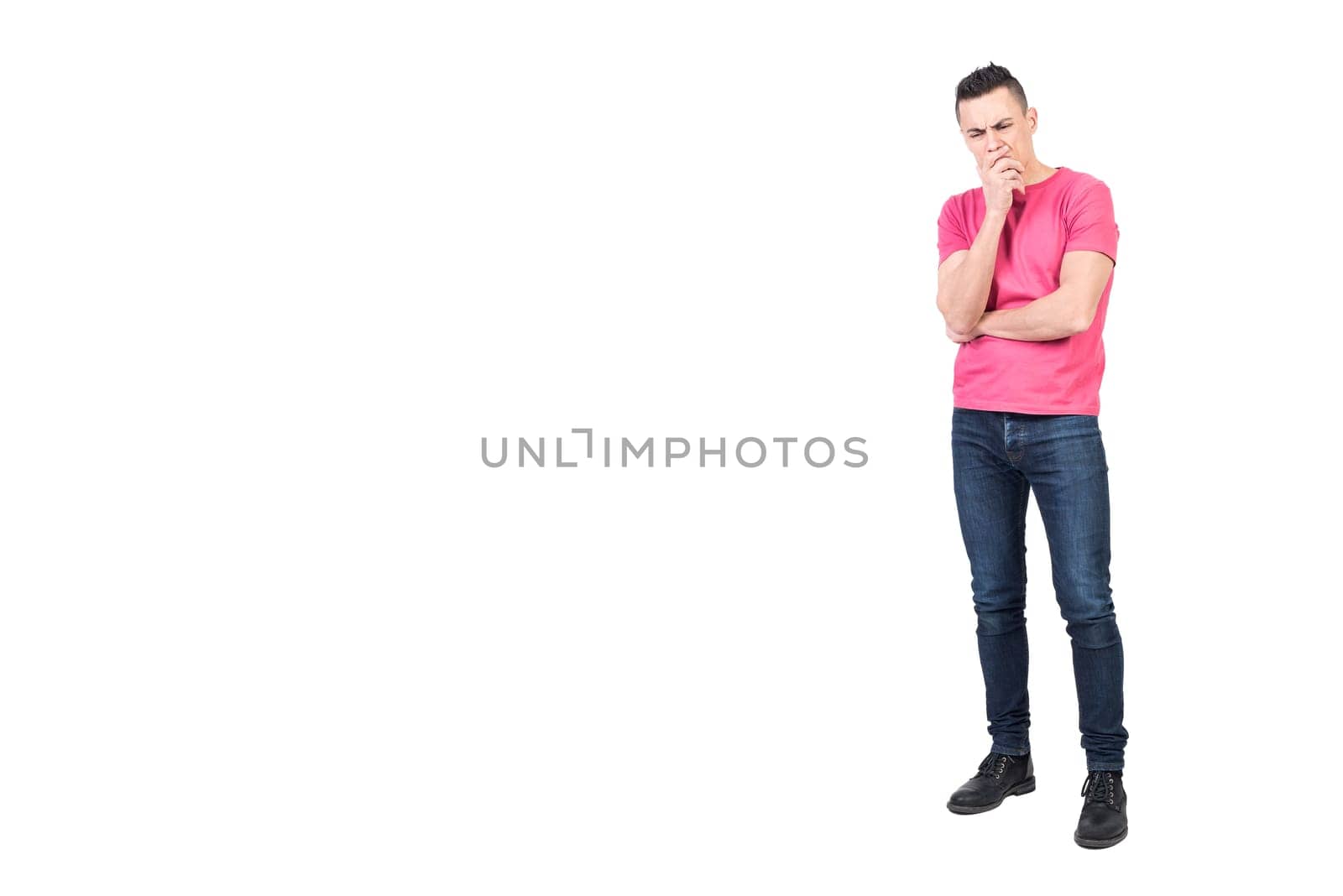 Full body of pensive male model in casual outfit touching chin while showing expression of confusion on white background