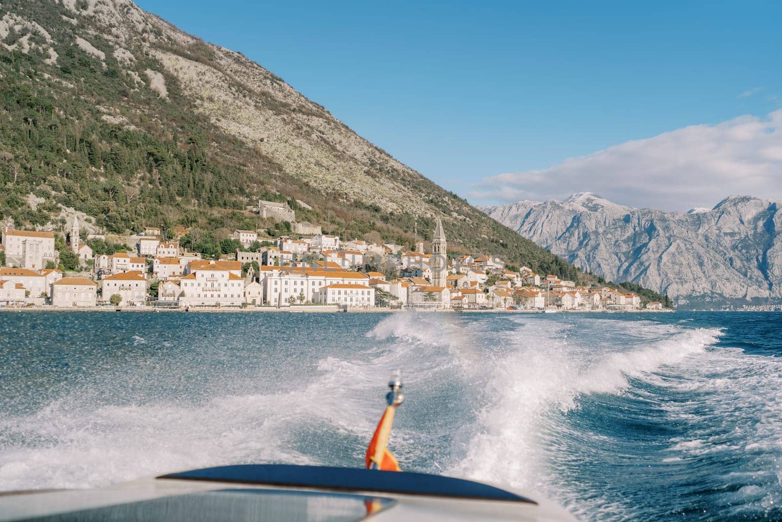 Motor boat sails on the sea, leaving a foam trail from the shore of Perast. Montenegro. High quality photo