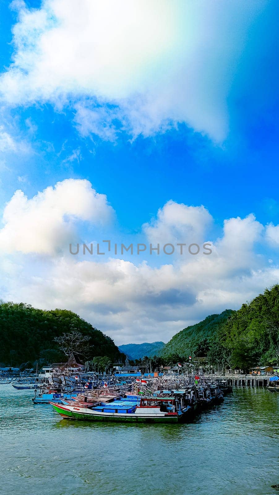 A large group of boats are floating on a lake. The sky is blue with some clouds