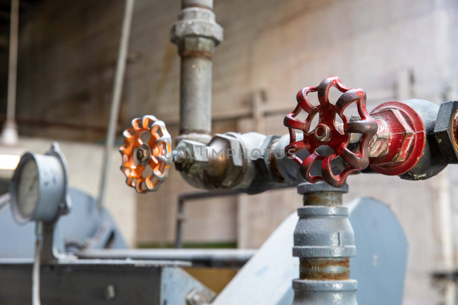 Close-up of industrial metal valves on mechanical pipes in a factory. The image depicts industrial engineering, equipment, and machinery in a manufacturing environment.