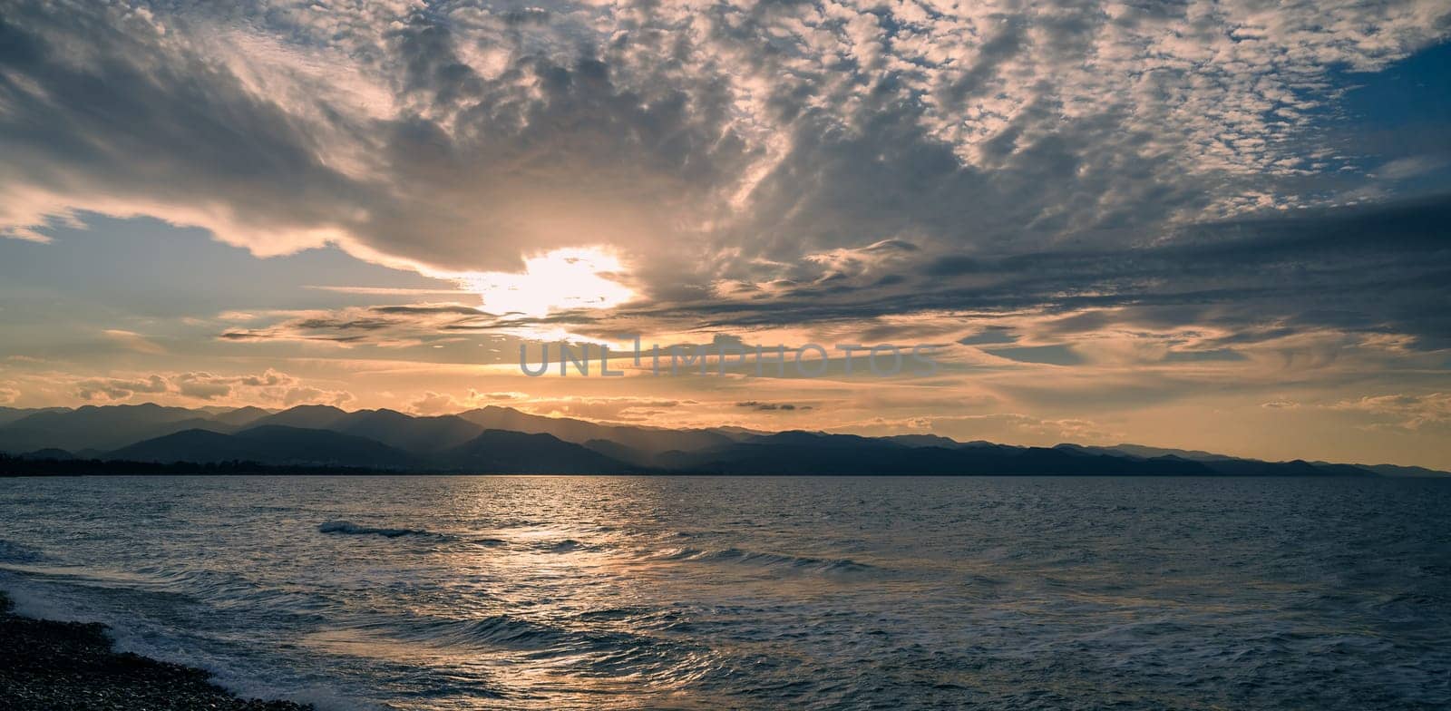 A beautiful sunset paints golden hues on calm ocean waters with clouds drifting above the serene landscape.