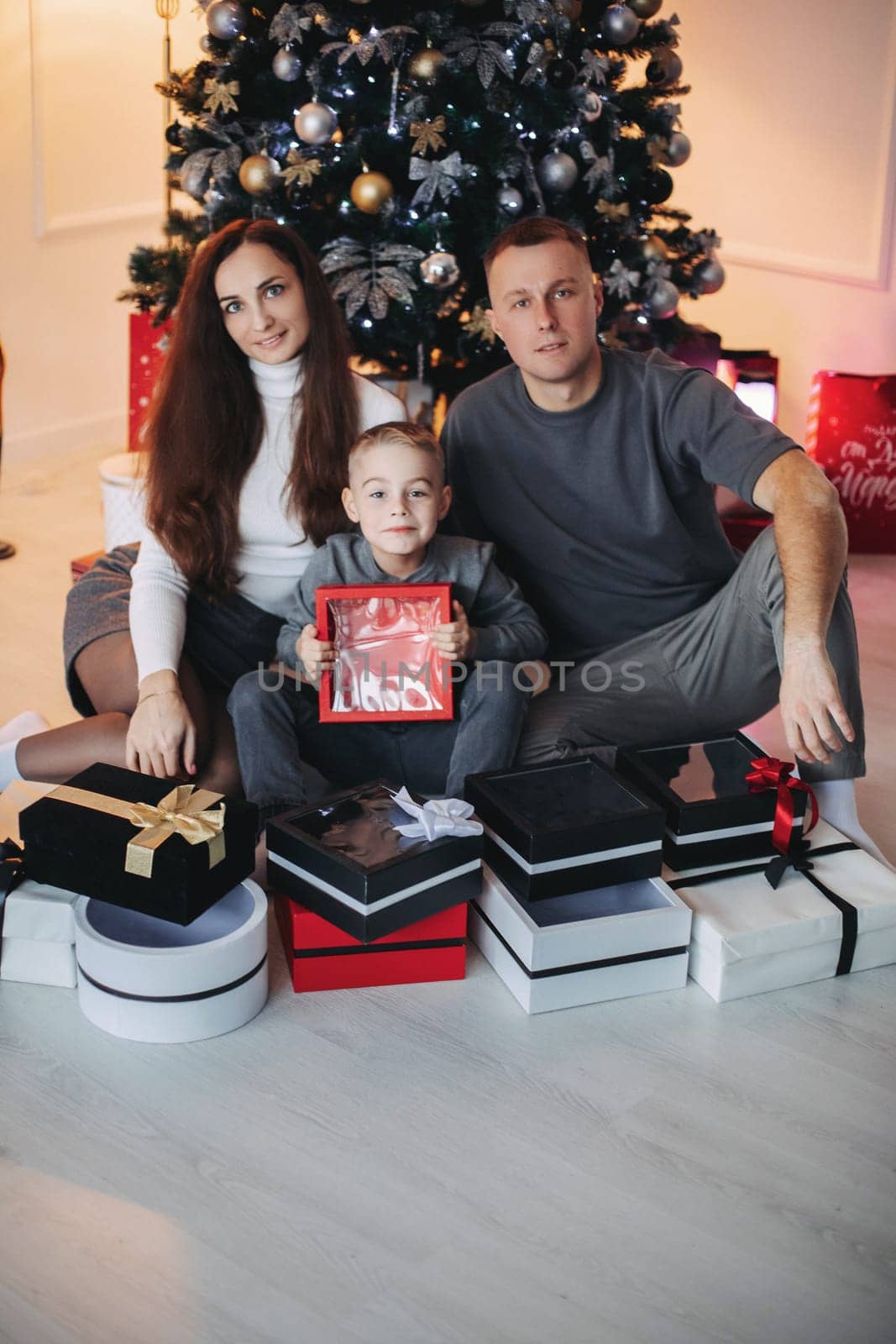 Happy family mom dad son at the Christmas tree on Christmas day.