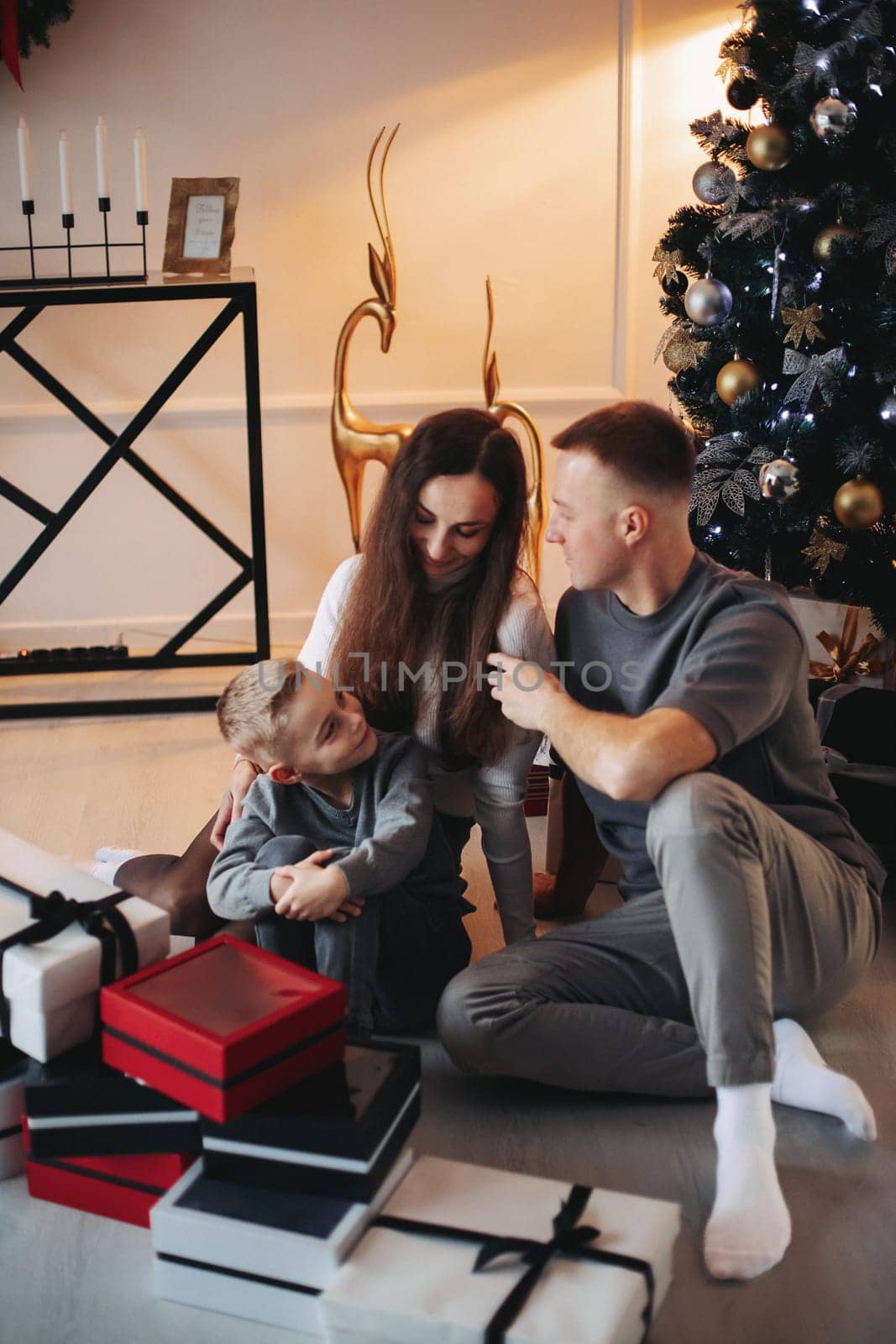Happy family mom dad son at the Christmas tree on Christmas day.