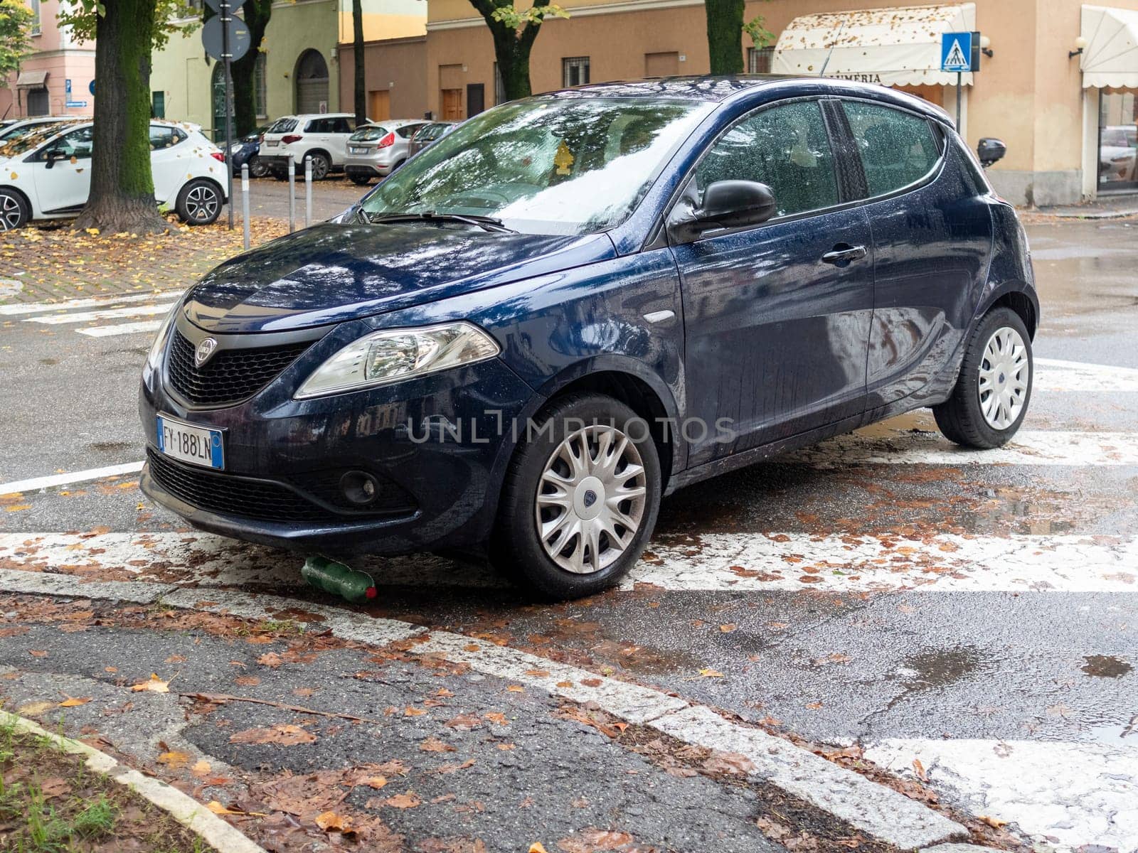 Cremona, Lombardy, Italy October 15th 2024 Dark blue lancia ypsilon improperly parked on pedestrian crossing with a plastic bottle underneath the front bumper on a rainy autumnal day