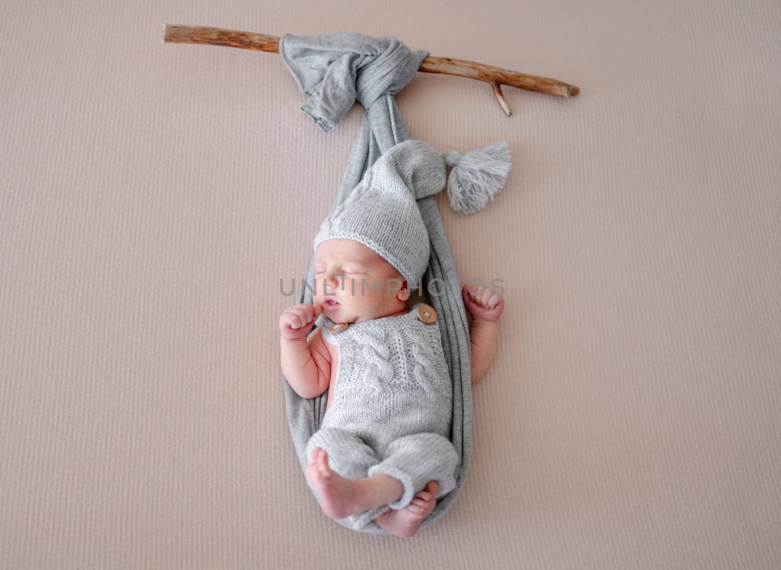 Newborn Baby Sleeps In Hammock Imitation On Branch During Photo Session