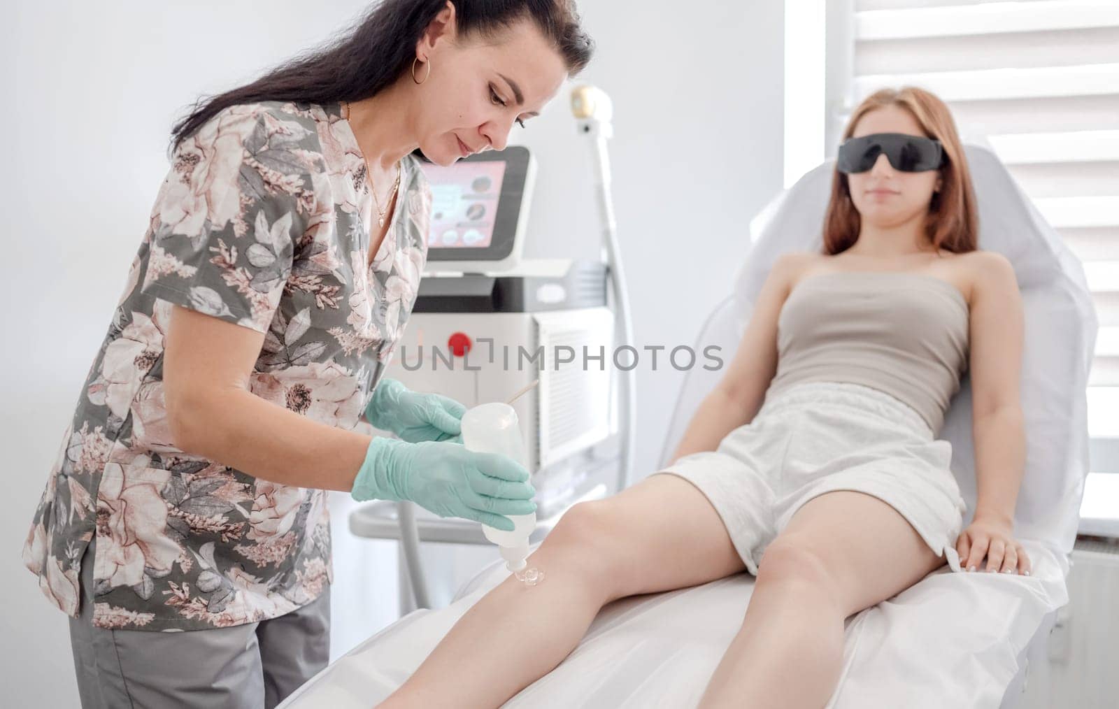 Master Of Laser Hair Removal Applies Gel To Girl'S Leg Before Procedure