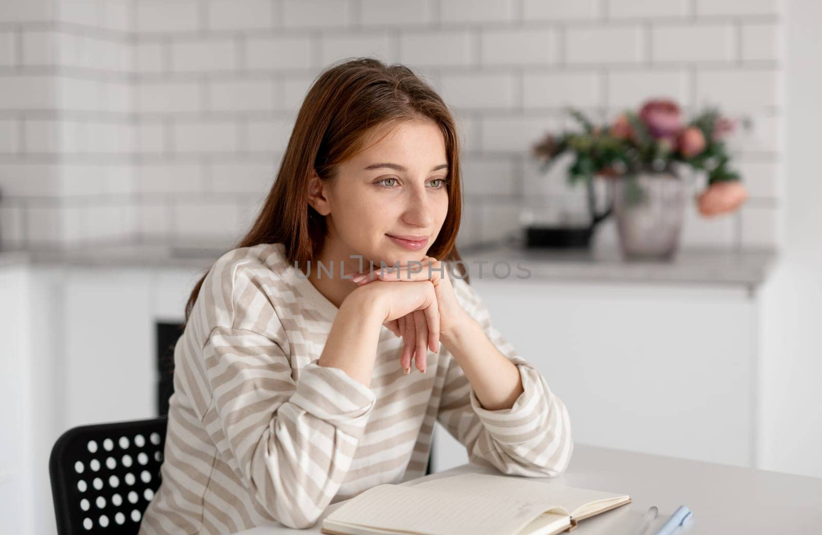 Thoughtful Teenage Girl Smiles At Home At The Table