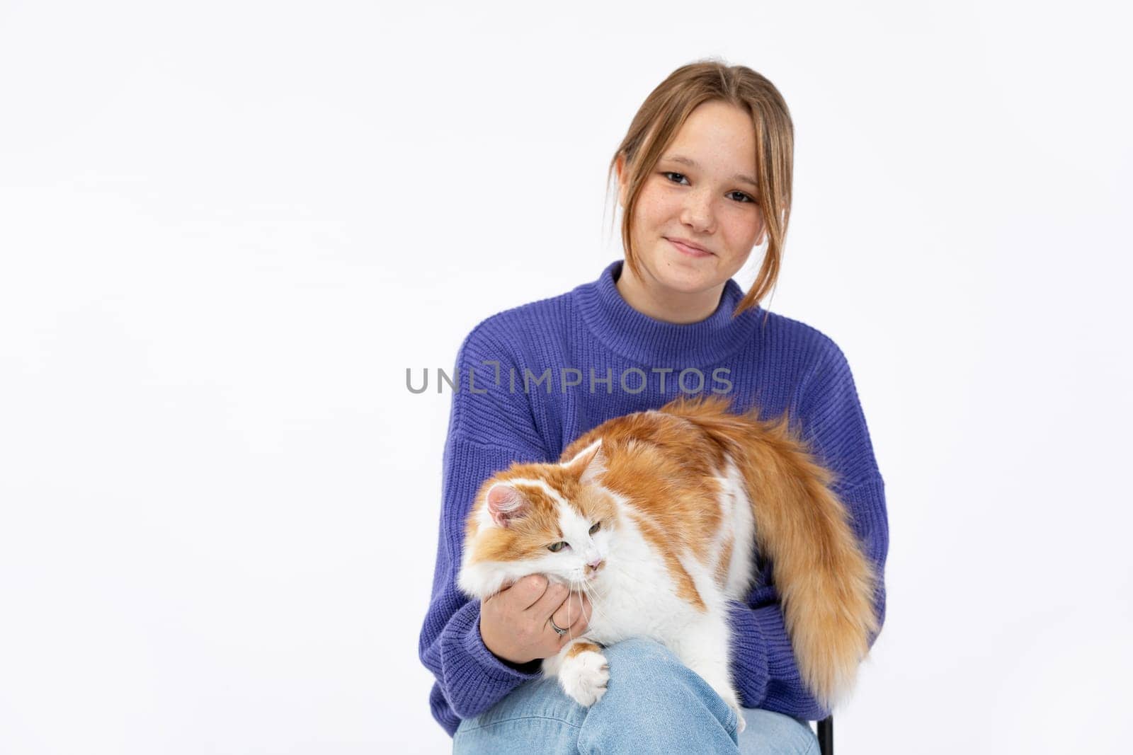 A girl smiles brightly with her adorable cat, showcasing joy and companionship in this playful moment