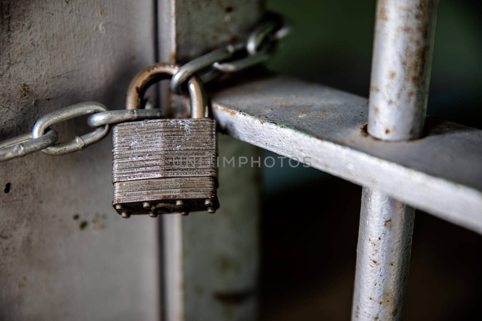 Close-up of a sturdy padlock on a rusted metal gate, symbolizing security and protection. The image captures the textures and strength of the metal components.