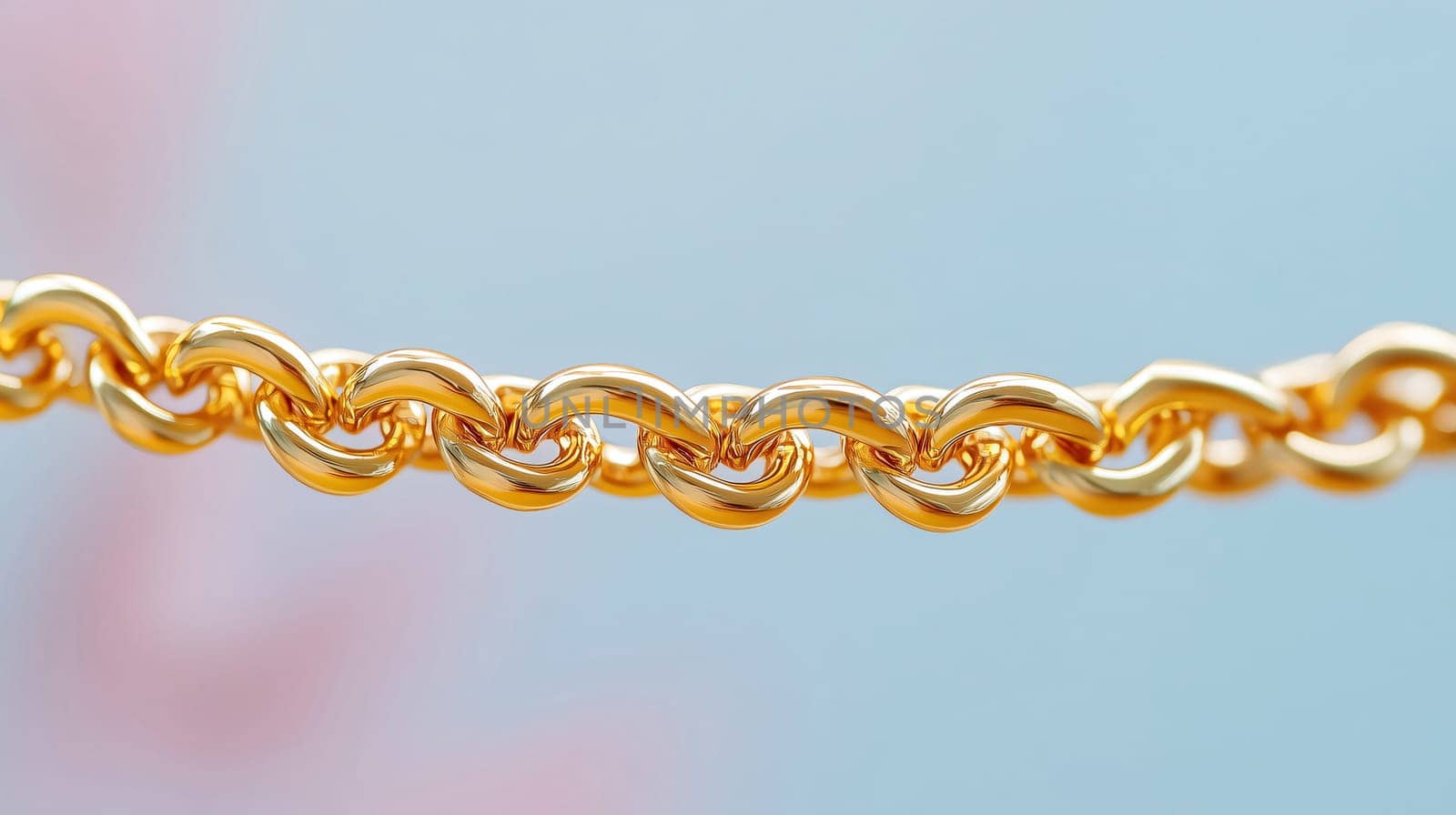 Shiny gold chain is hanging in front of a pastel blue and pink background