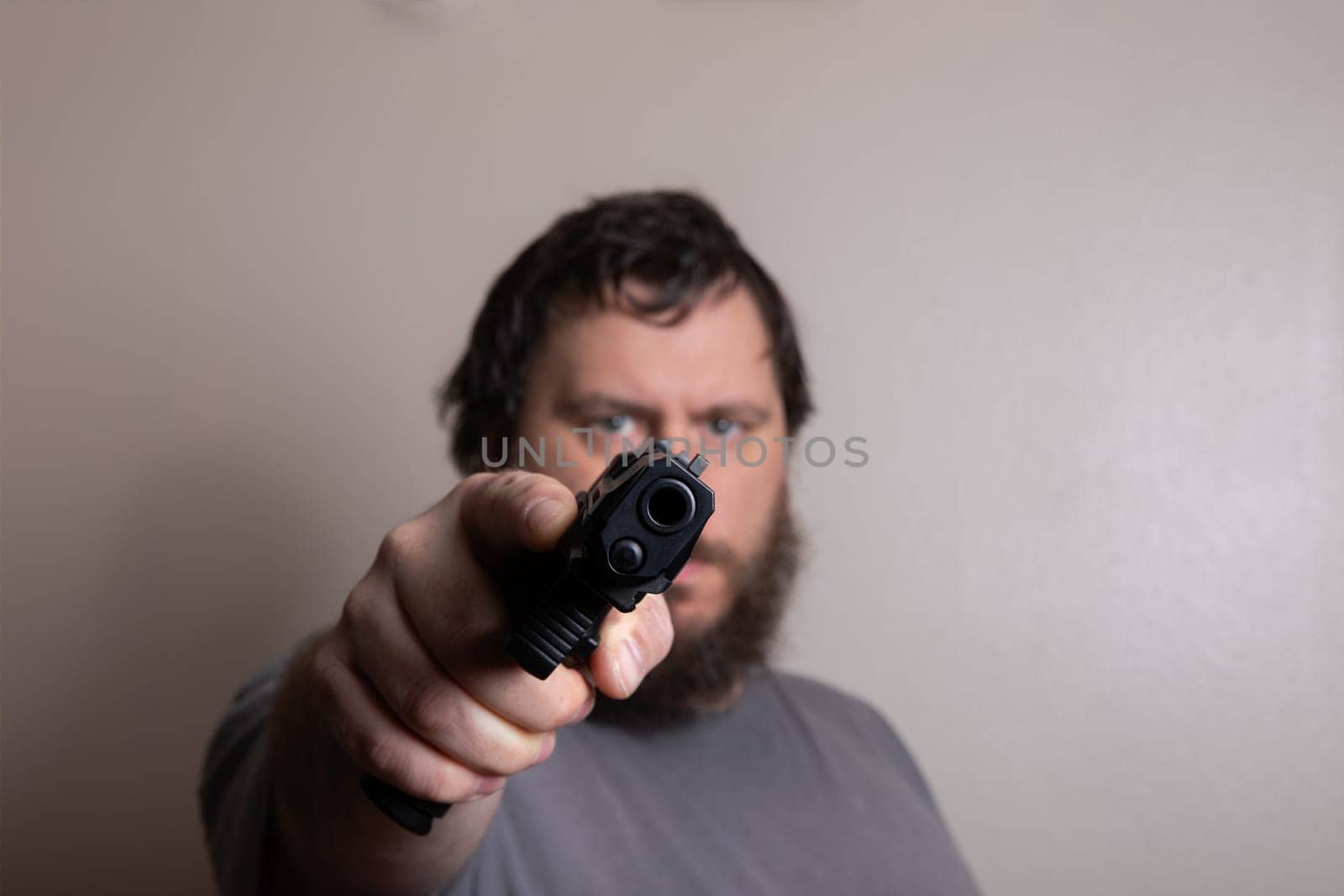 A focused man pointing a gun directly at the camera, emphasizing intensity and confrontation. The close-up captures a sense of urgency and tension.