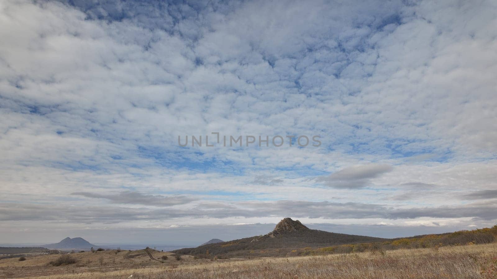 A panoramic view of rolling hills and dramatic cloud formations above a peaceful landscape during the afternoon in a rural area.