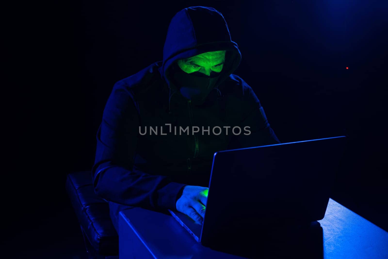 Hackers wear hoods to cover their faces. Hacking to steal important information. Use a computer to release malware viruses Ransom and harass organizations. He sitting in the dark room with neon light