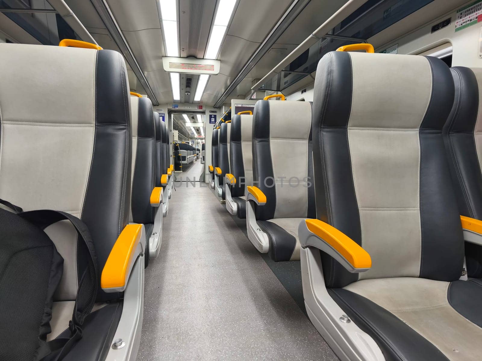 an empty train carriage with rows of seats and a clear view down the aisle.