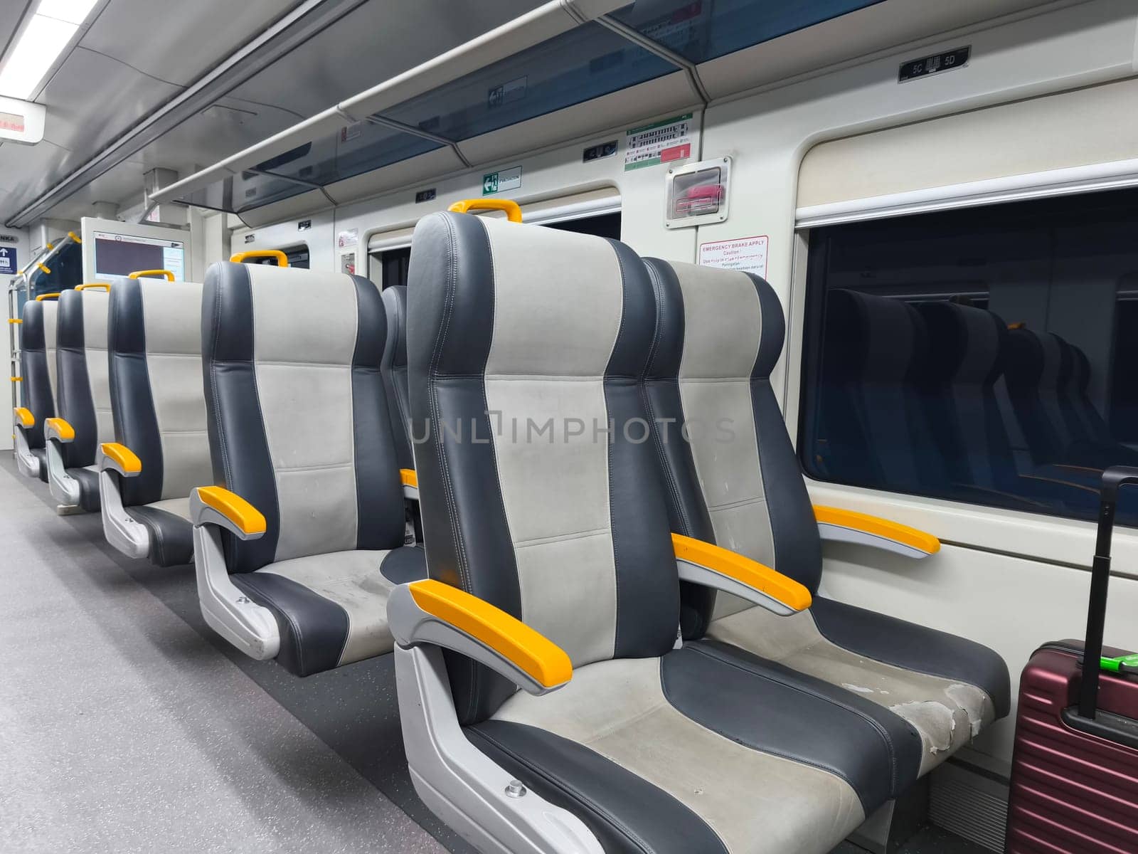 an empty train carriage with rows of seats and a clear view down the aisle.
