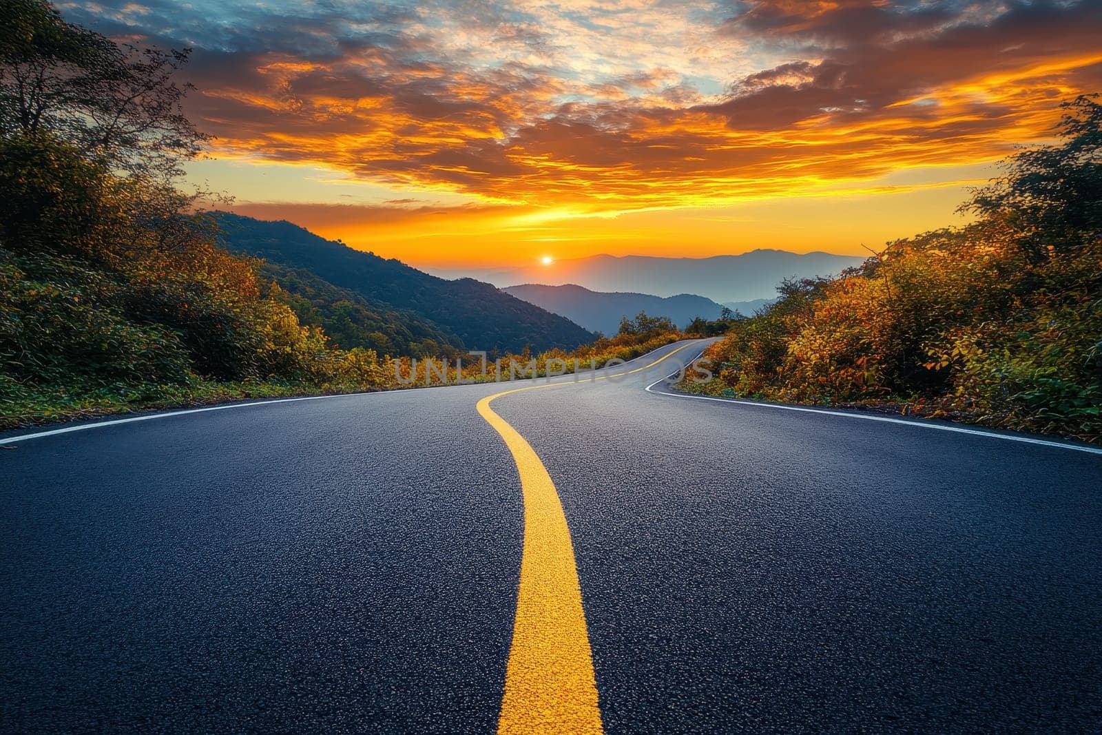Scenic view of a winding road leading through lush green hills against the backdrop of majestic mountains on a sunny day..