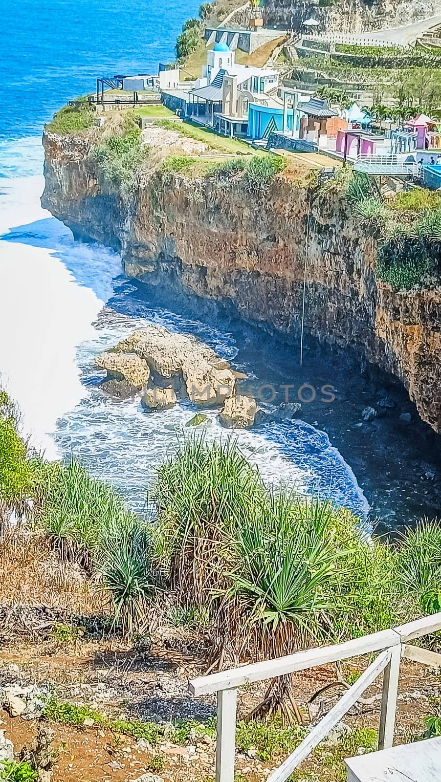 Stunning view of a rocky cliff overlooking the vast, blue ocean with waves crashing below. The harmonious blend of sea and sky offers a sense of peace and tranquility.