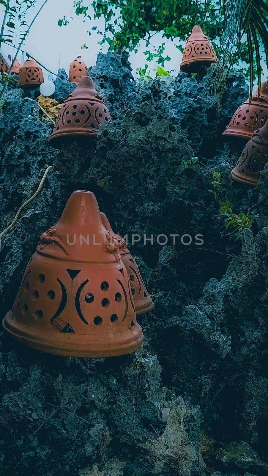 Decorative terracotta pots placed on rugged, rocky terrain juxtaposed with lush green foliage, creating a rustic and artistic outdoor scene. Ideal for themes of nature, craftsmanship, and aesthetics.