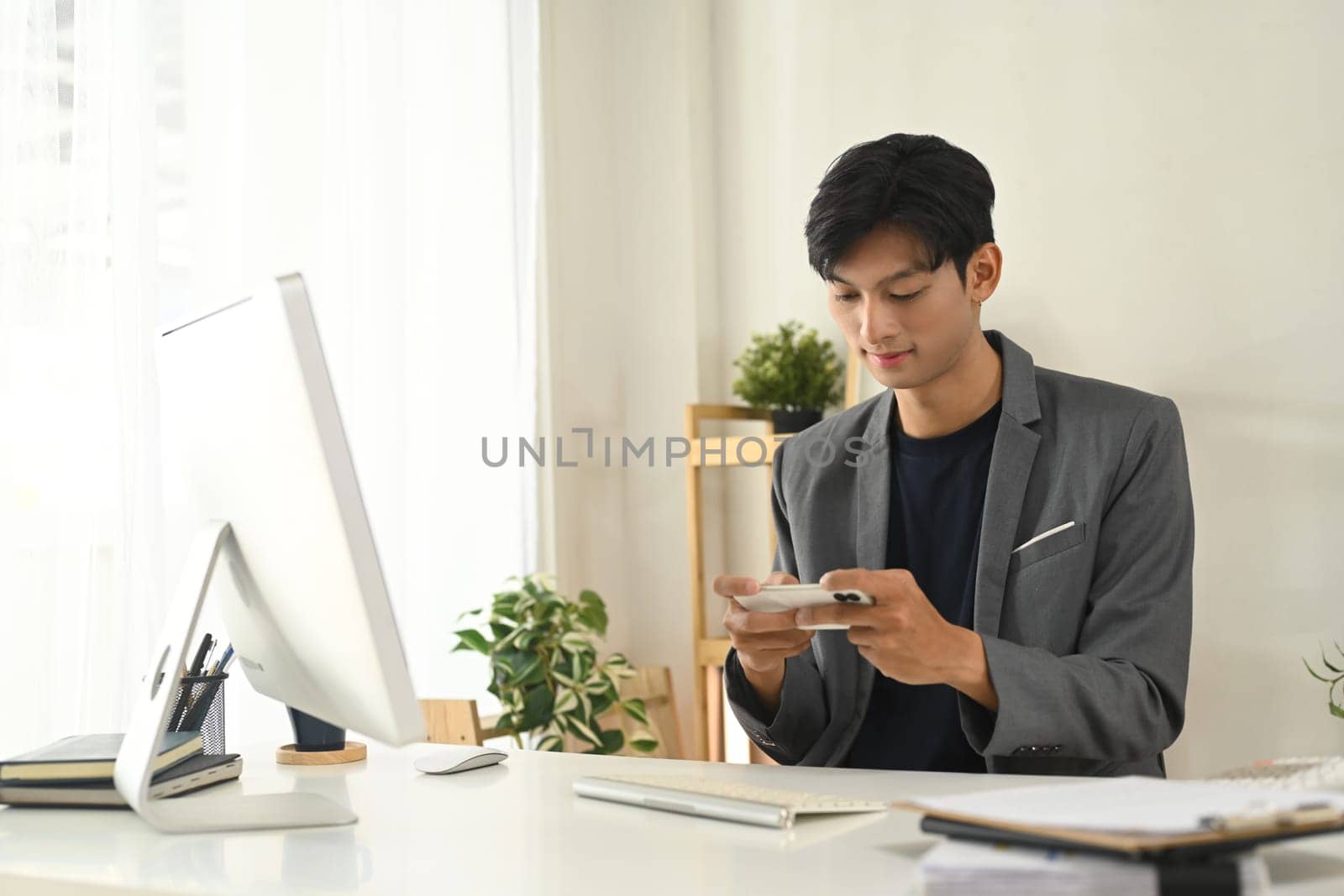 Young entrepreneur taking a break from work and using smartphone.