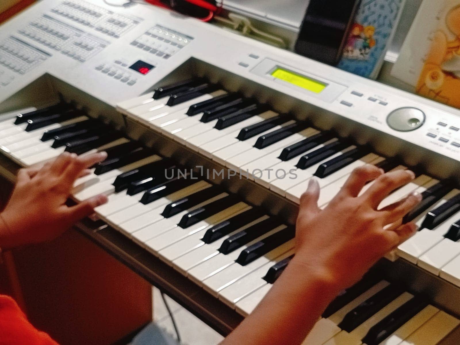 Close-up of young hands skillfully playing an electronic organ, capturing a moment of musical practice and creativity in a cozy music room.