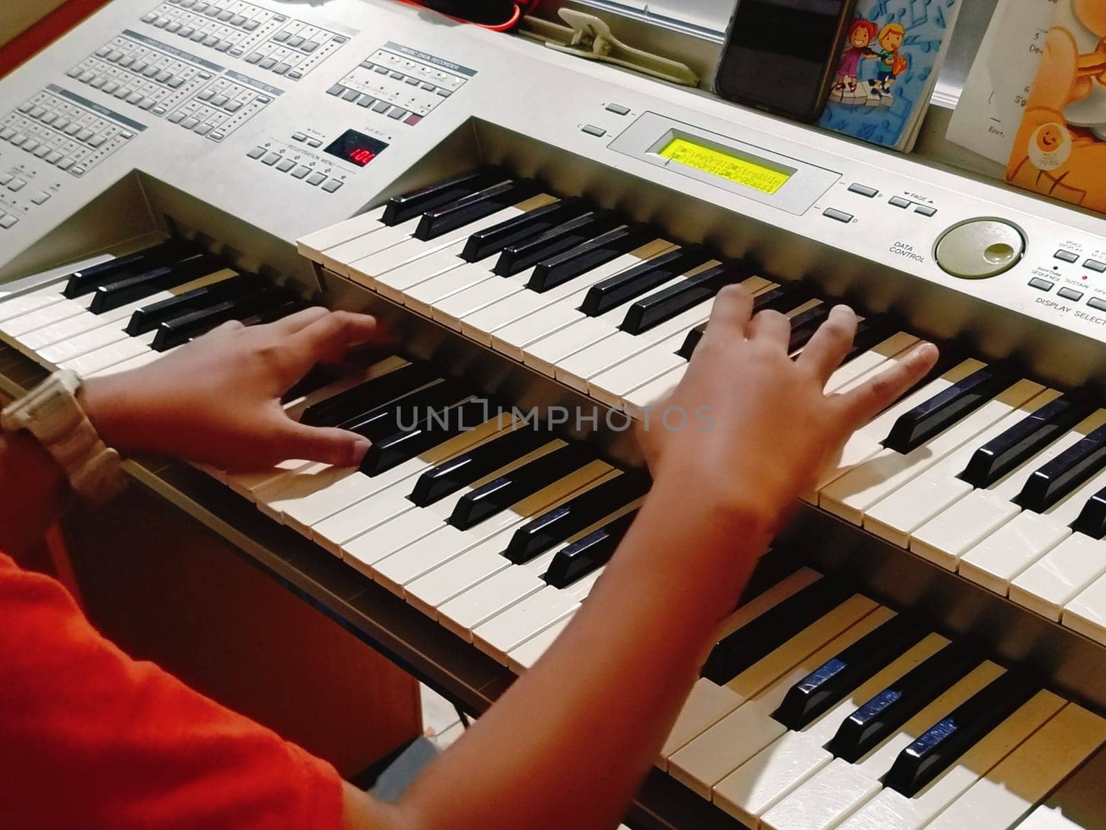 Close-up of young hands skillfully playing an electronic organ, capturing a moment of musical practice and creativity in a cozy music room.