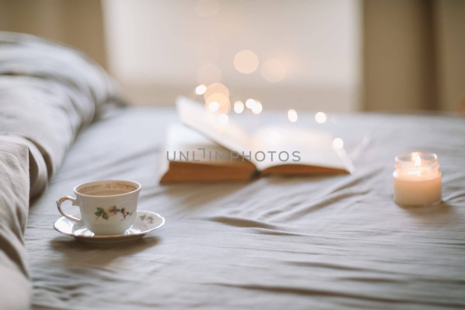 A cup of coffee and a book lying on the bed in a white bedroom. High quality photo