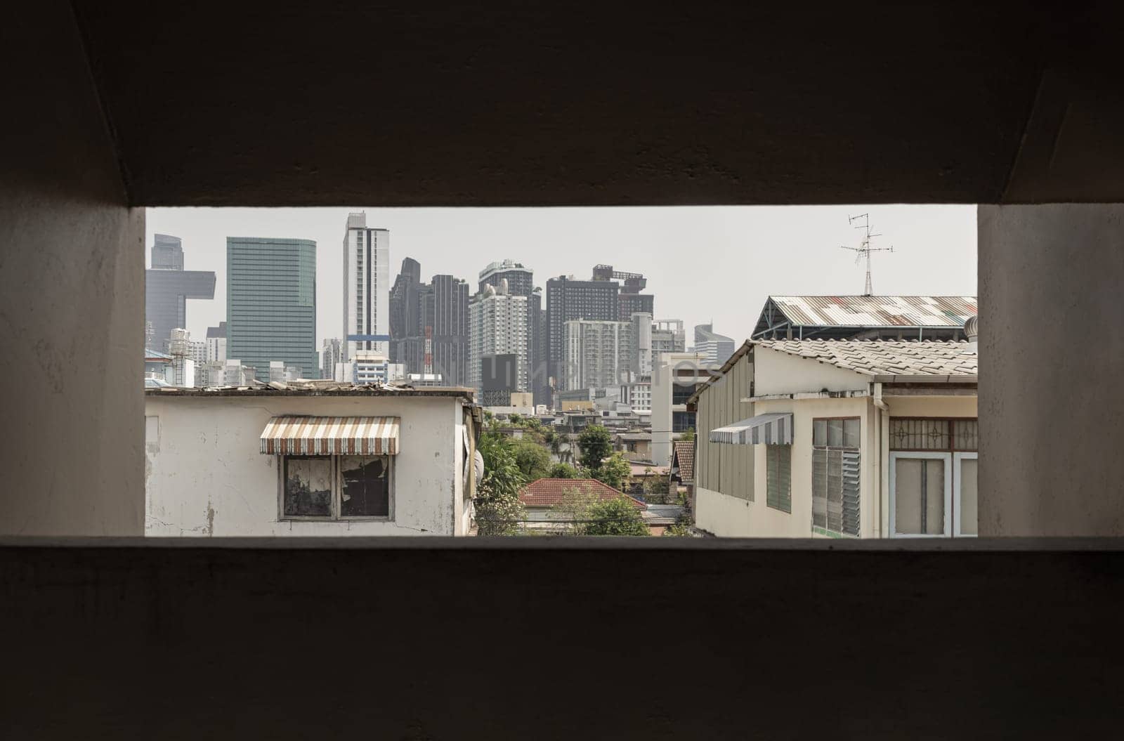 Bangkok, Thailand - 27 Feb 2023 - Cityscape view of Bangkok with a mix of Old house and Modern skyscrapers background. Architectural View of Old and New Buildings in Contrasting Classical and Modern Designs, Look through the window frame in Old building, Space for text, Selective Focus.