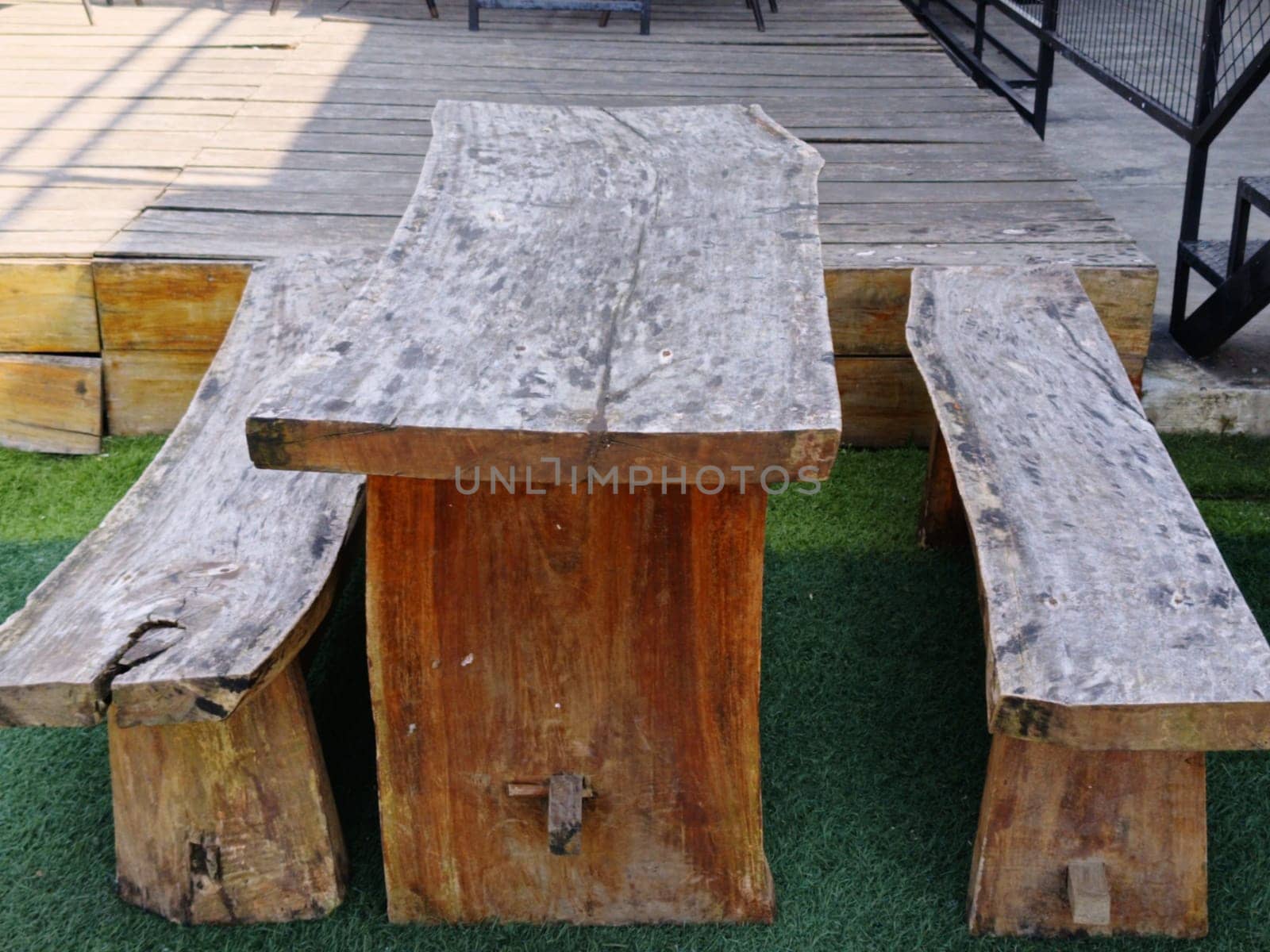 A rustic wooden table and benches set on an outdoor patio, showcasing natural, handcrafted design. Ideal for gatherings, creating a cozy and organic atmosphere.