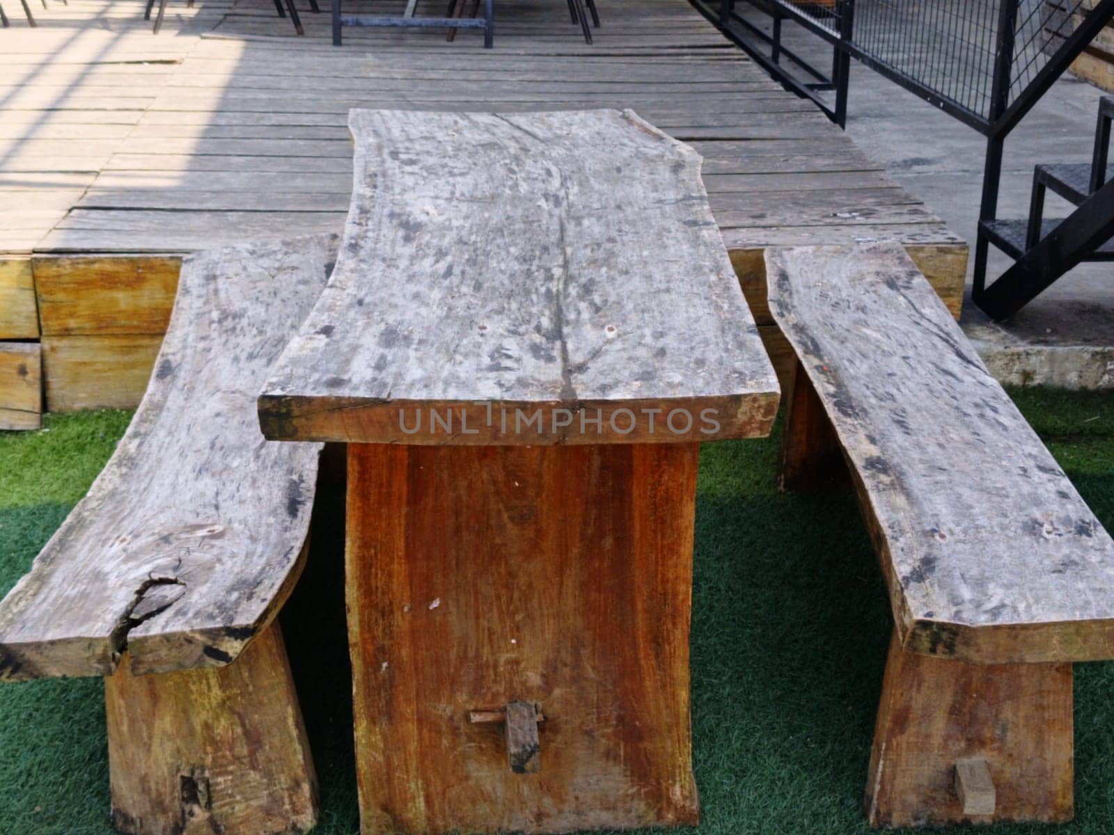 A rustic wooden table and benches set on an outdoor patio, showcasing natural, handcrafted design. Ideal for gatherings, creating a cozy and organic atmosphere.