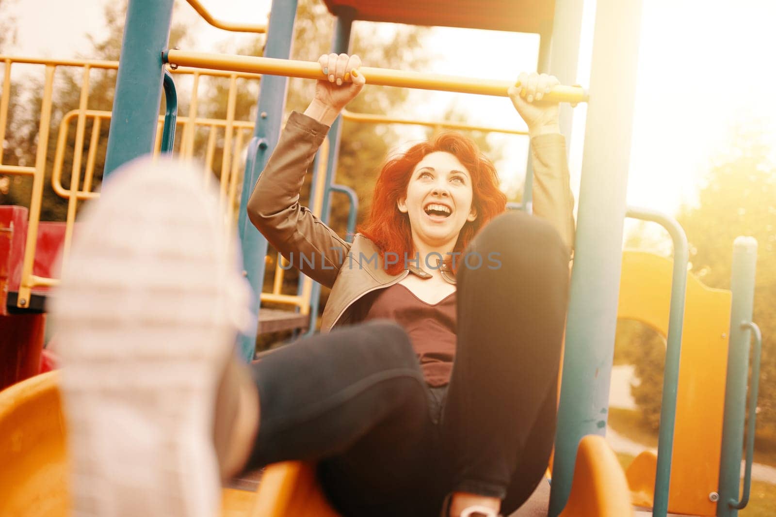A joyful woman sliding down a colorful playground slide, embodying bliss and happiness in the warm sun