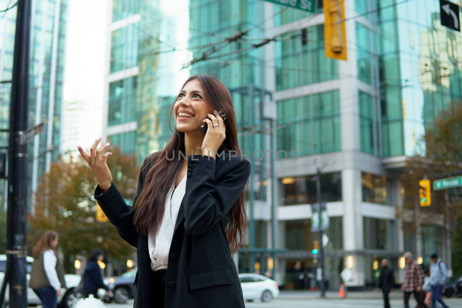 Young hispanic businesswoman talking on her cell phone while walking on city urban street.