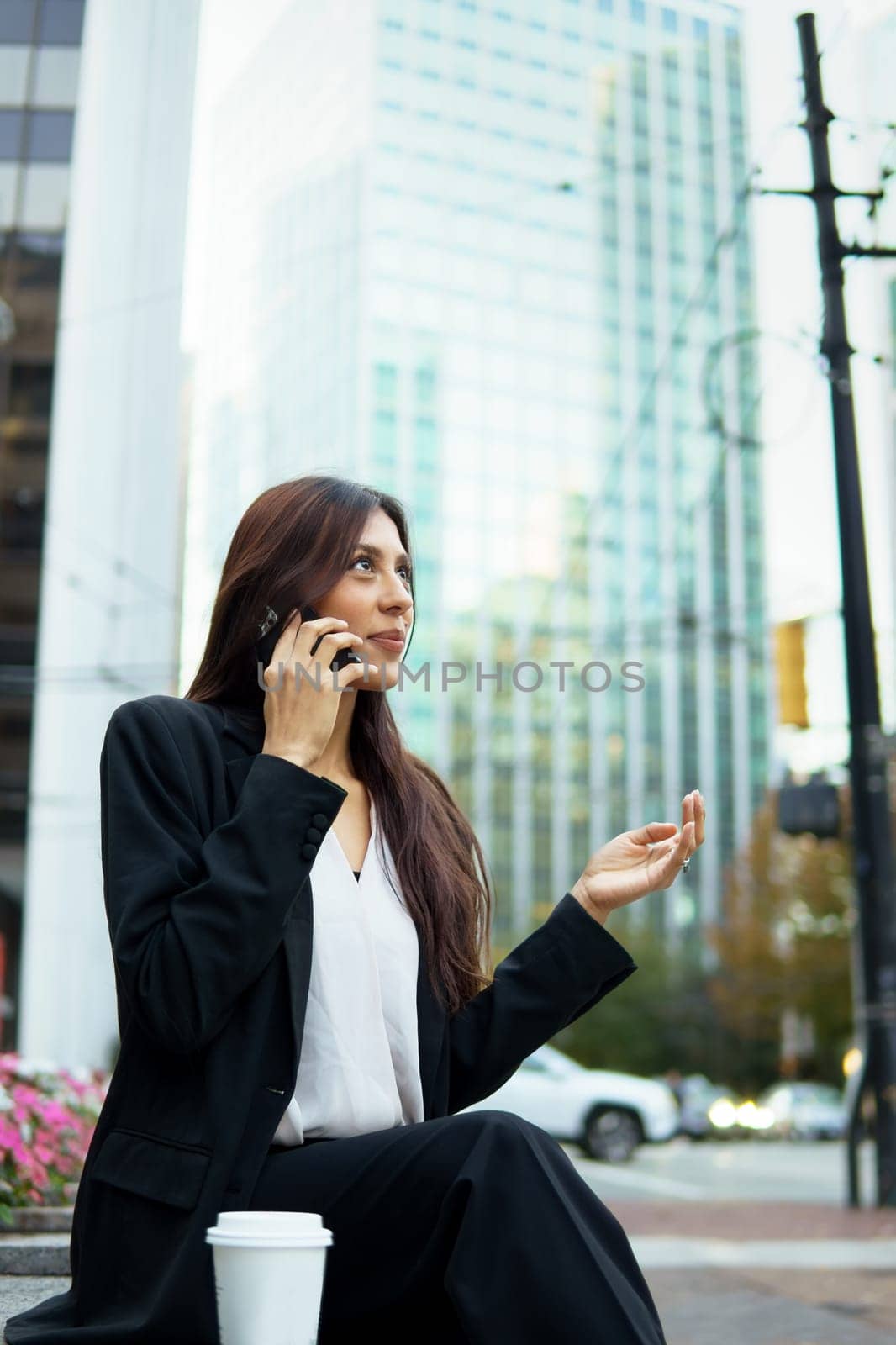 Young hispanic businesswoman talking on her cell phone while walking on city urban street.