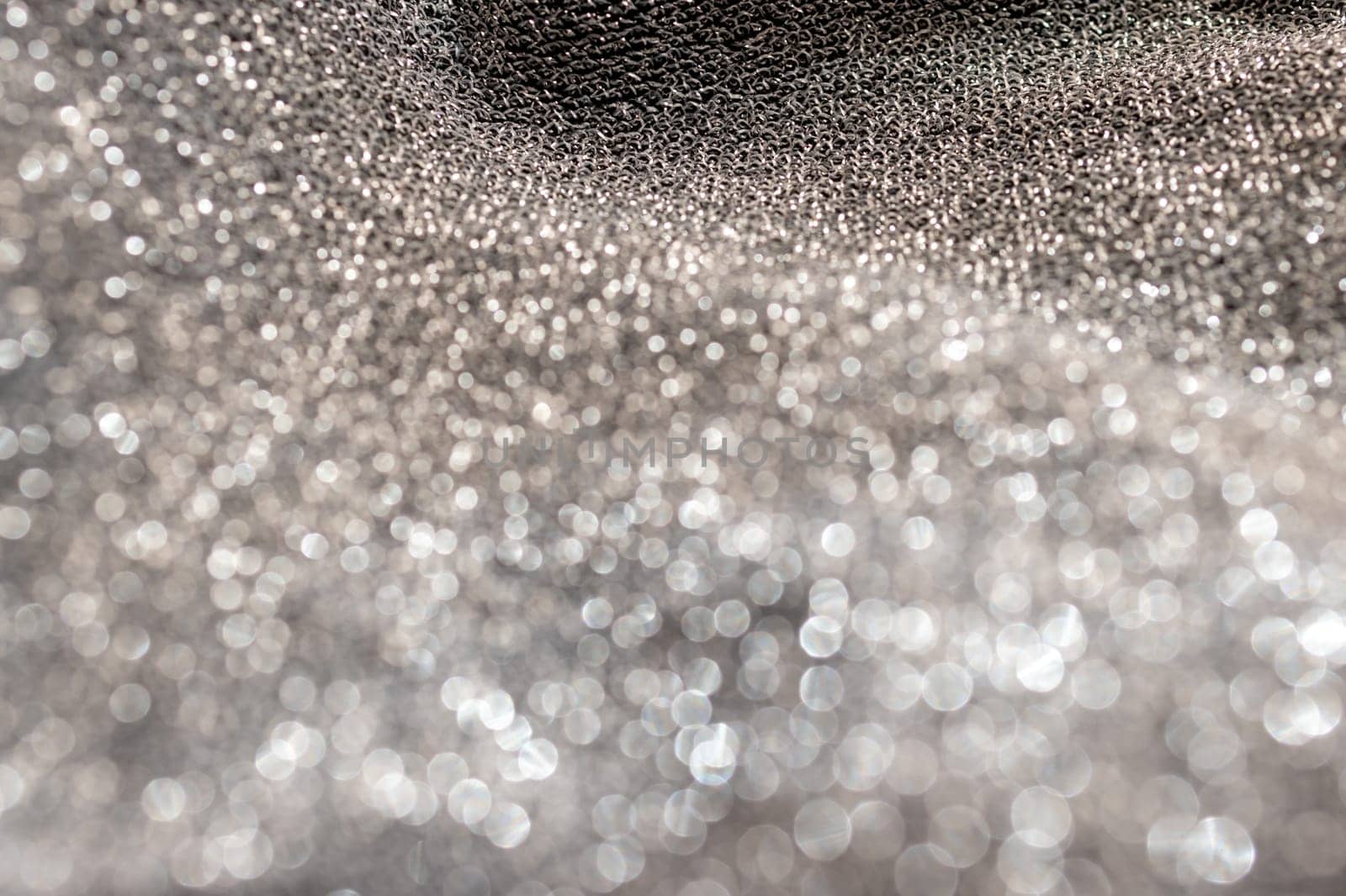 Silver glitter background material.Horizontal blurred metallic surface. Pure silver wire mesh. Wavy fabric with glitter. Used for backgrounds of fashion products