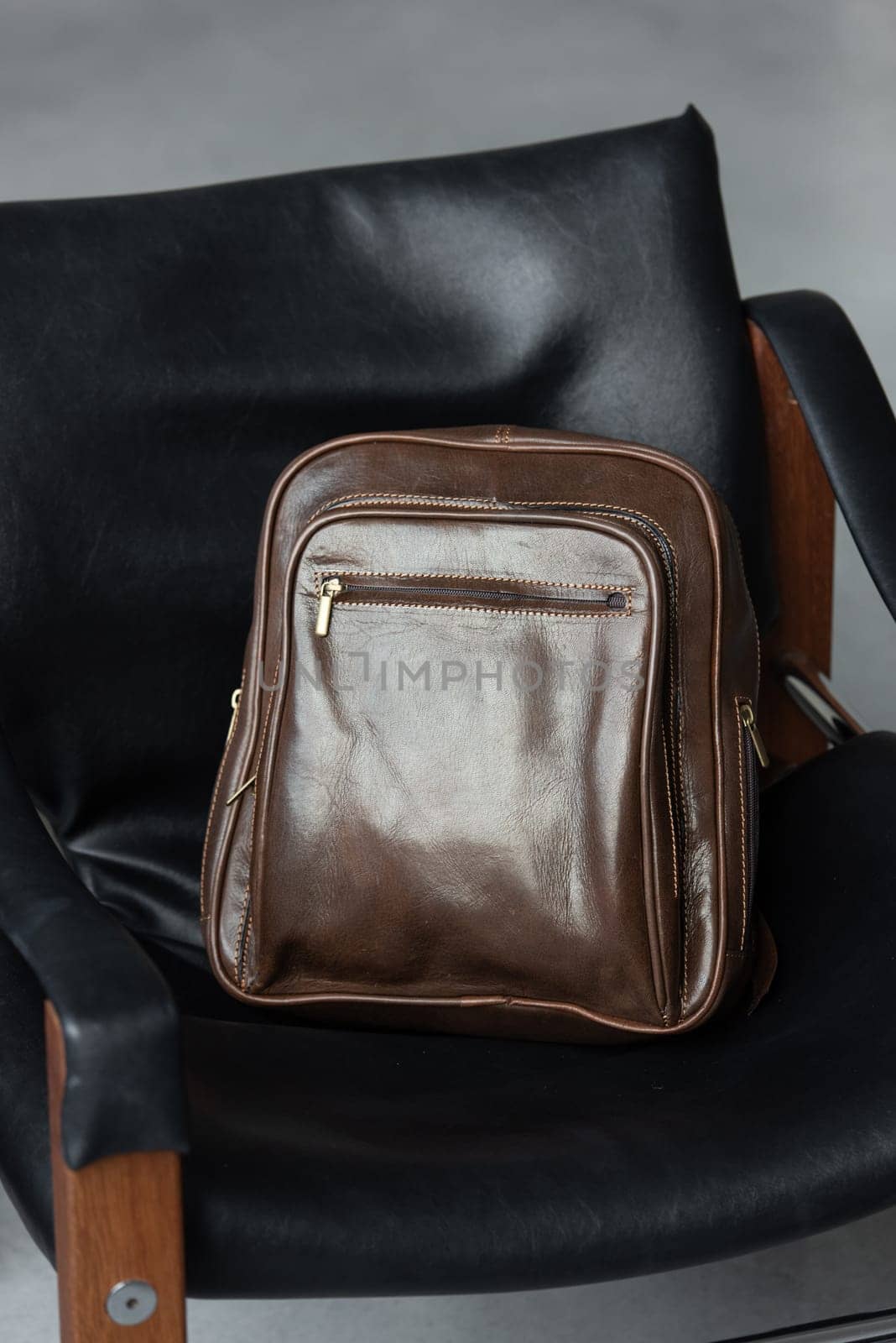Brown leather backpack on the stylish chair.