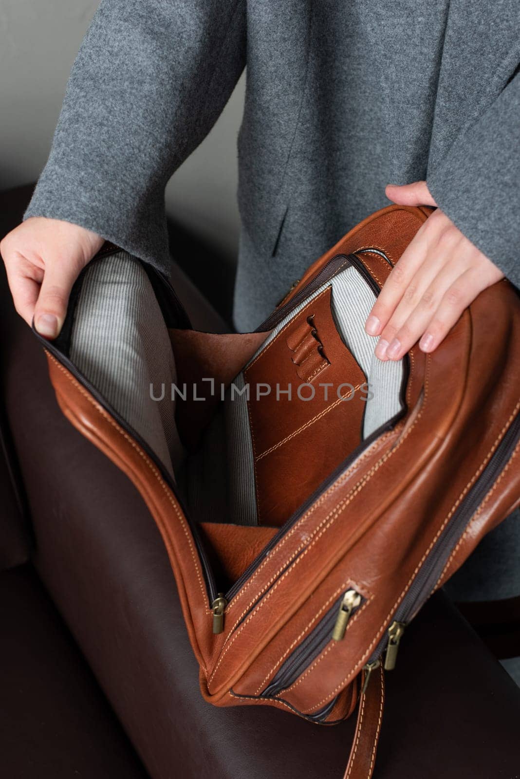 woman holds a brownleather backpack. open, empty bag.