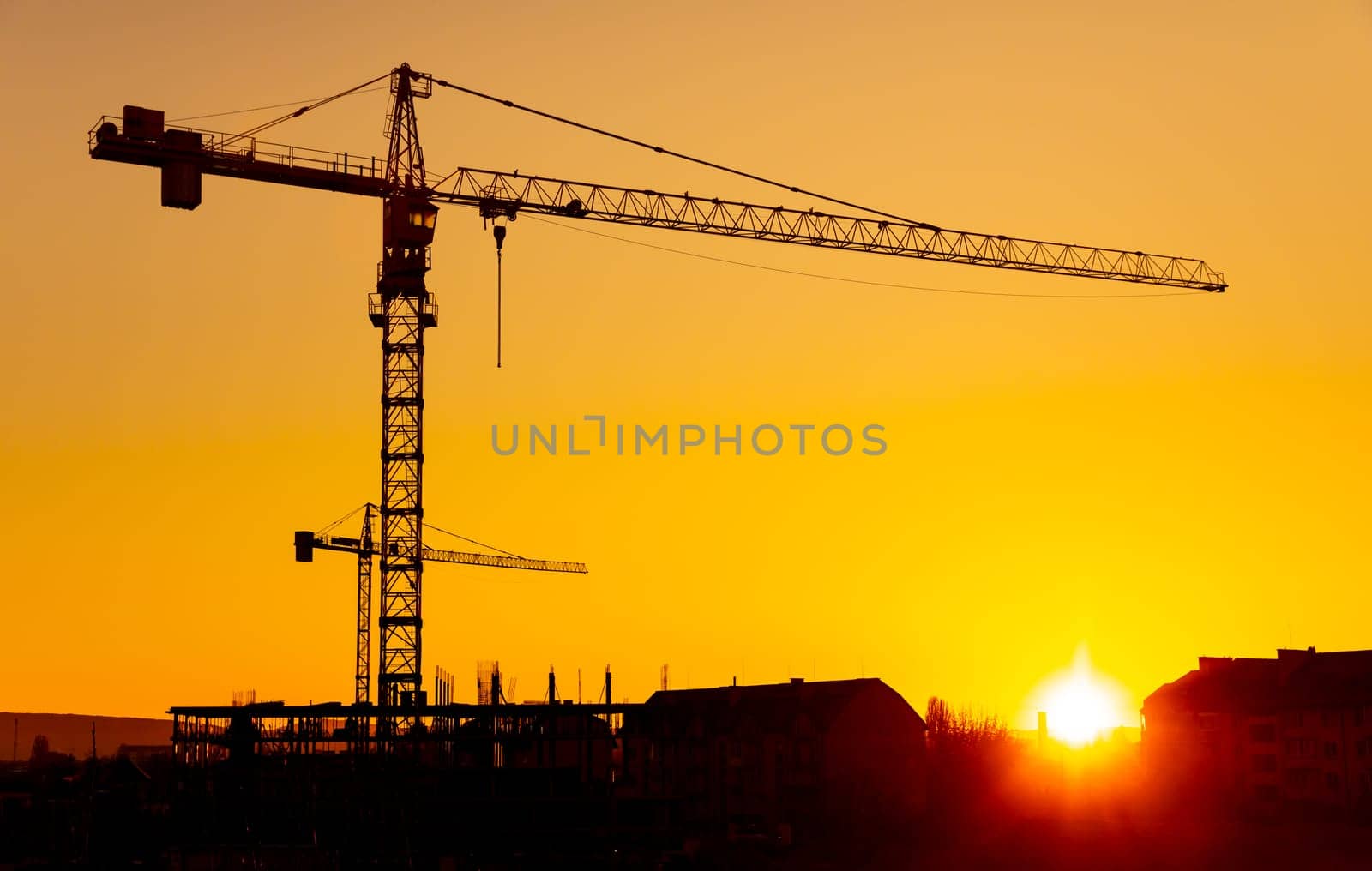 Construction boom in western Ukraine. A construction crane silhouetted against the warm glow of an early morning sky.