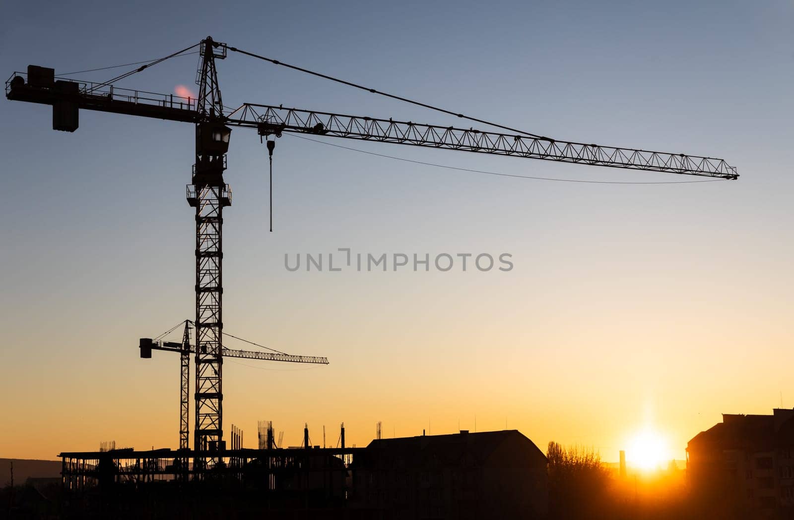 Construction boom in western Ukraine. A construction crane silhouetted against the warm glow of an early morning sky.