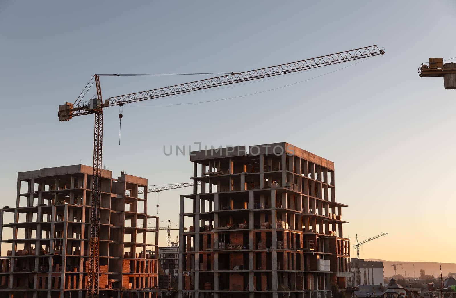 Construction boom in western Ukraine. A construction crane silhouetted against the warm glow of an early morning sky.