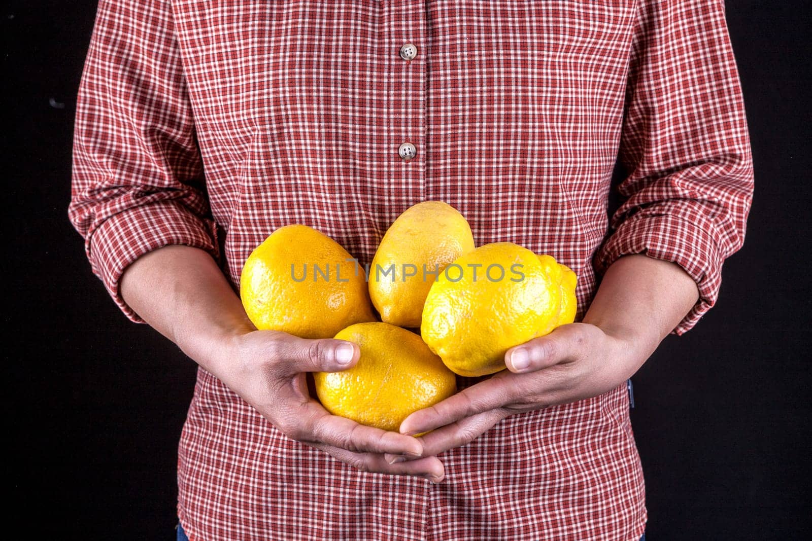 A studio image of an unidentified woman holding a bunch of lemons.