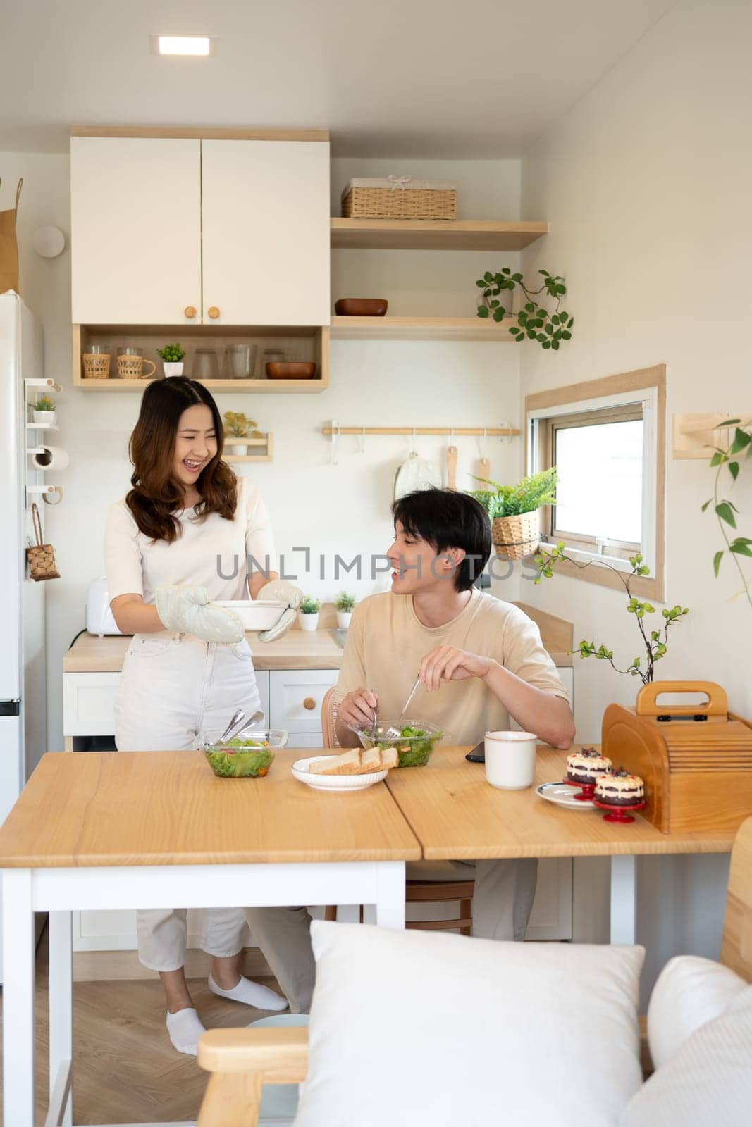 Young asian woman serving healthy lunch to her husband in a minimalist kitchen.